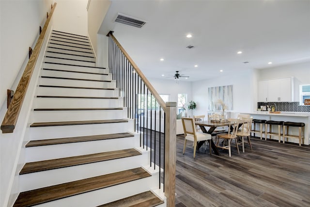 staircase with hardwood / wood-style floors and ceiling fan