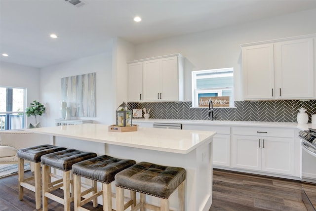 kitchen featuring backsplash, white cabinets, a kitchen breakfast bar, and a kitchen island