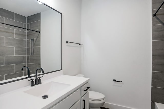 bathroom featuring a tile shower, vanity, and toilet