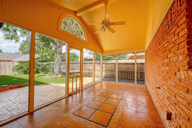 unfurnished sunroom with ceiling fan, plenty of natural light, and lofted ceiling with beams