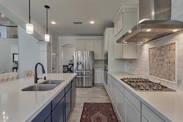 kitchen featuring stainless steel appliances, sink, decorative light fixtures, tasteful backsplash, and range hood