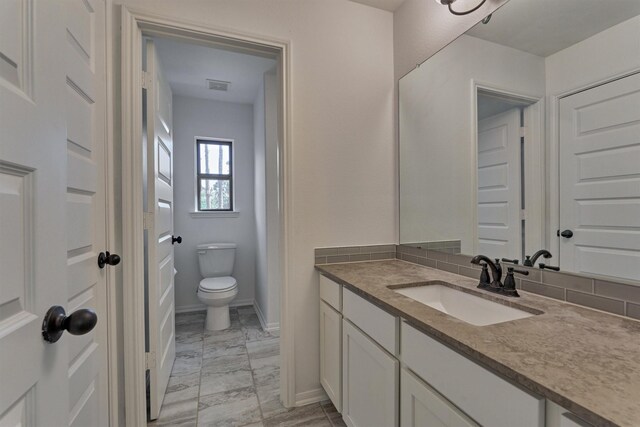 bathroom with toilet, tasteful backsplash, and vanity