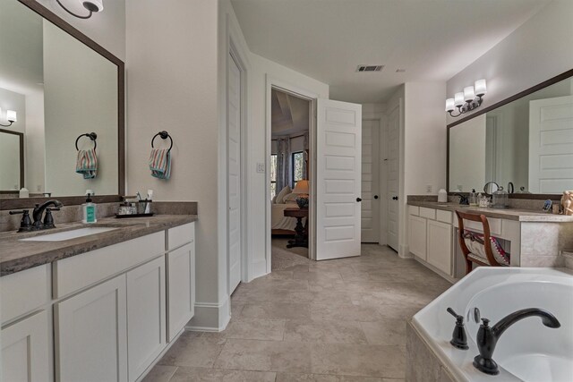 bathroom featuring a relaxing tiled tub and vanity