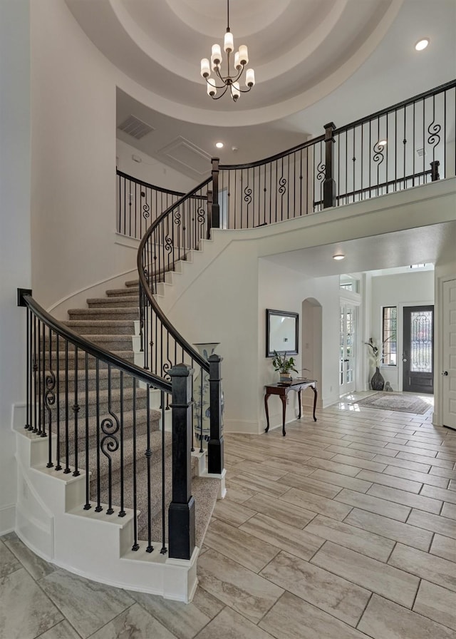 entryway featuring a towering ceiling, french doors, a tray ceiling, and a chandelier