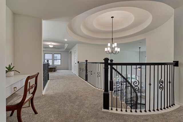 corridor featuring carpet, a chandelier, and a tray ceiling