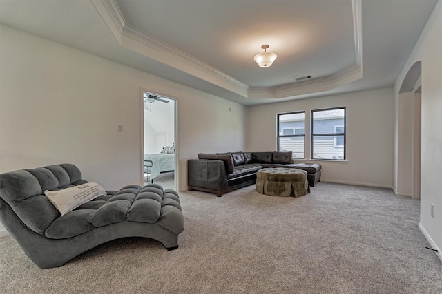 carpeted living room featuring a raised ceiling, ceiling fan, and ornamental molding