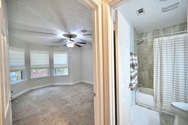 bathroom with a textured ceiling, toilet, ceiling fan, and shower / bath combo with shower curtain