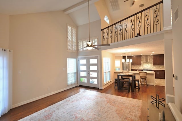 interior space featuring beamed ceiling, ceiling fan with notable chandelier, and high vaulted ceiling