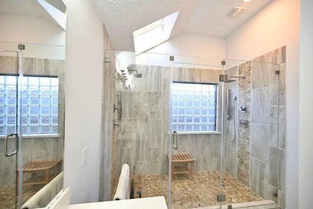 bathroom featuring a textured ceiling, a skylight, and walk in shower