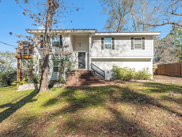 raised ranch with entry steps, metal roof, fence, a front yard, and brick siding