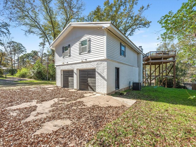 view of side of home featuring a yard, cooling unit, a deck, and a garage