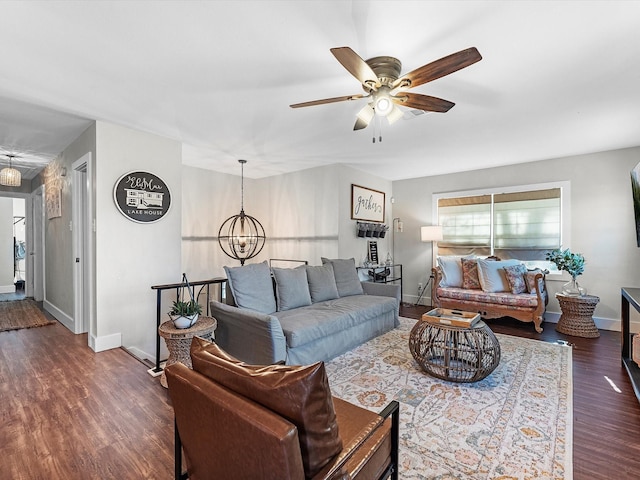 living area featuring dark wood-style floors, baseboards, and ceiling fan with notable chandelier