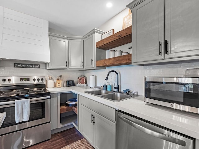 kitchen featuring a sink, stainless steel appliances, light countertops, open shelves, and backsplash