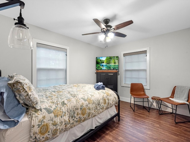 bedroom with a ceiling fan, multiple windows, baseboards, and wood finished floors