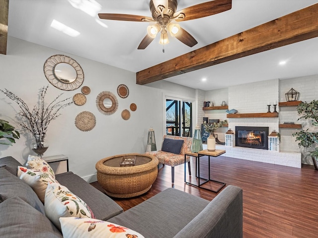 living room featuring baseboards, ceiling fan, wood finished floors, a brick fireplace, and beam ceiling