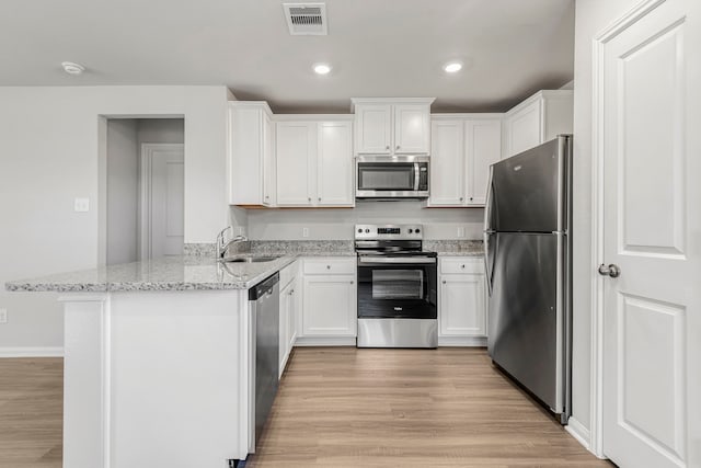 kitchen with white cabinets, light stone counters, kitchen peninsula, and stainless steel appliances