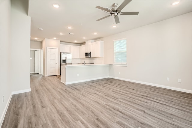 kitchen featuring kitchen peninsula, appliances with stainless steel finishes, ceiling fan, light hardwood / wood-style flooring, and white cabinets