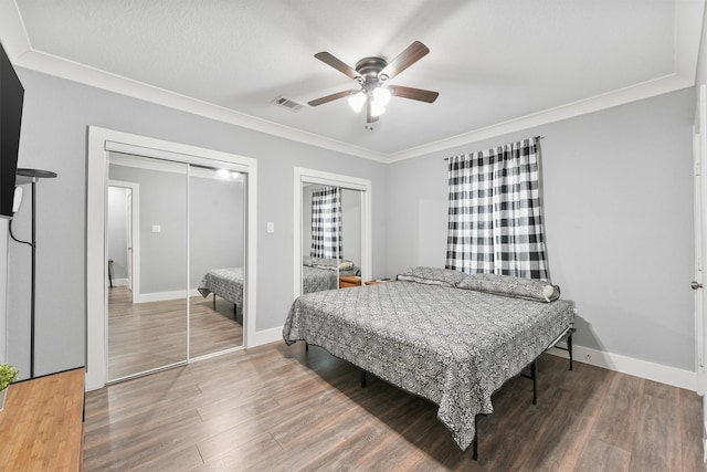 bedroom with multiple closets, ceiling fan, hardwood / wood-style floors, and crown molding