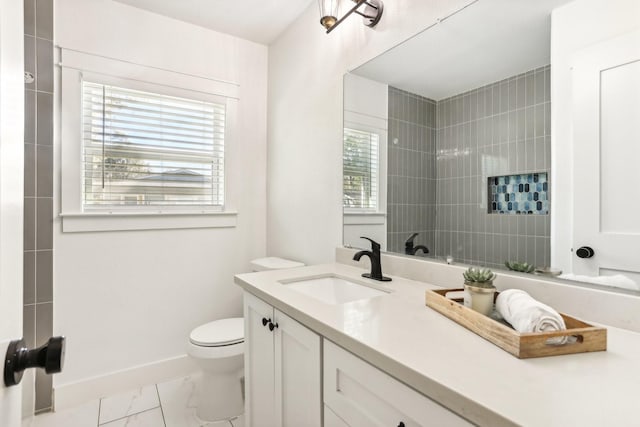 bathroom with tiled shower, vanity, a healthy amount of sunlight, and toilet