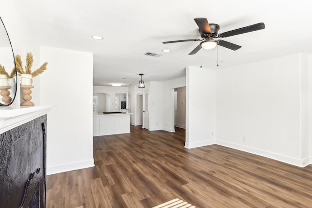 unfurnished living room with dark hardwood / wood-style flooring and ceiling fan