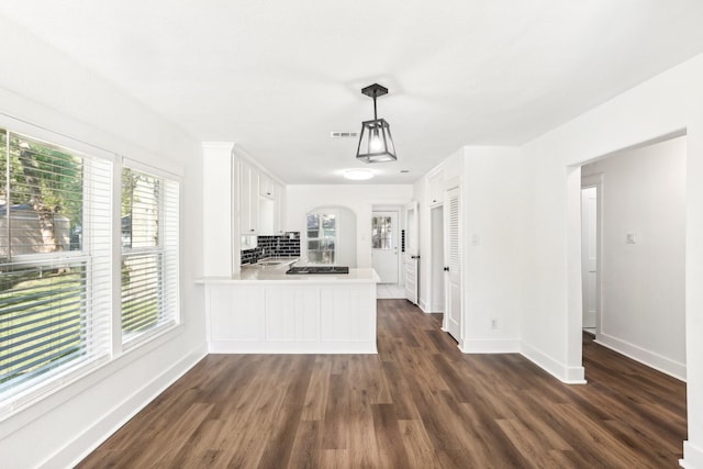 kitchen with kitchen peninsula, dark hardwood / wood-style flooring, white cabinetry, and hanging light fixtures