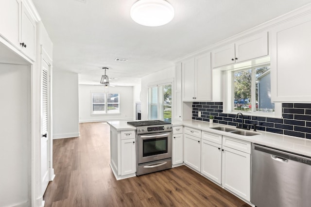 kitchen with sink, appliances with stainless steel finishes, white cabinetry, dark hardwood / wood-style flooring, and kitchen peninsula