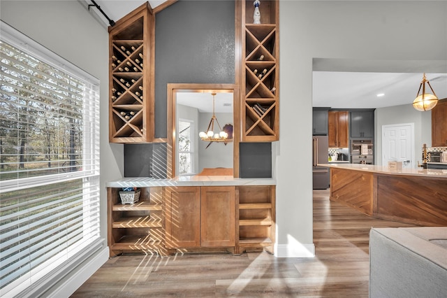 wine area featuring wood-type flooring and an inviting chandelier