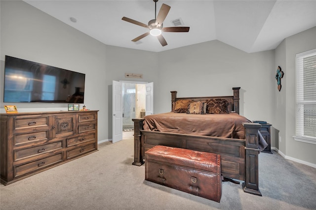 carpeted bedroom with multiple windows, ceiling fan, vaulted ceiling, and ensuite bath