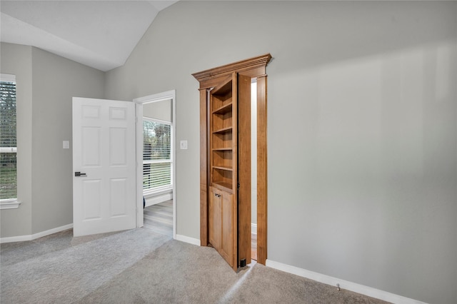 hall with light carpet and vaulted ceiling