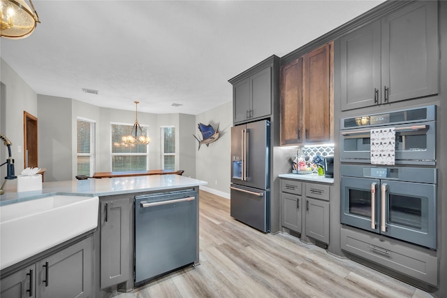 kitchen with sink, a chandelier, gray cabinets, pendant lighting, and stainless steel appliances