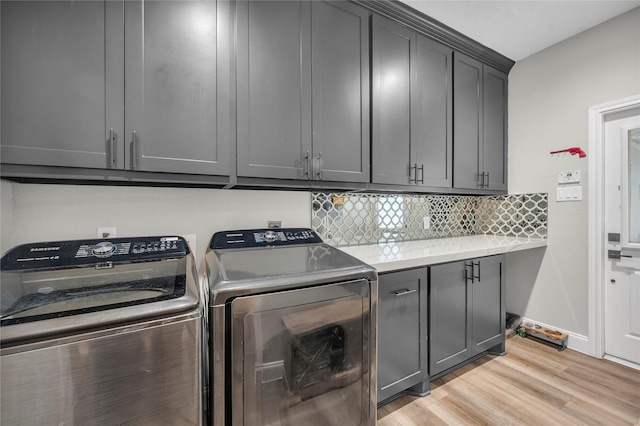 laundry area with cabinets, light hardwood / wood-style floors, and washing machine and clothes dryer