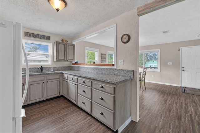 kitchen featuring sink, dark wood-type flooring, light stone countertops, a textured ceiling, and white fridge