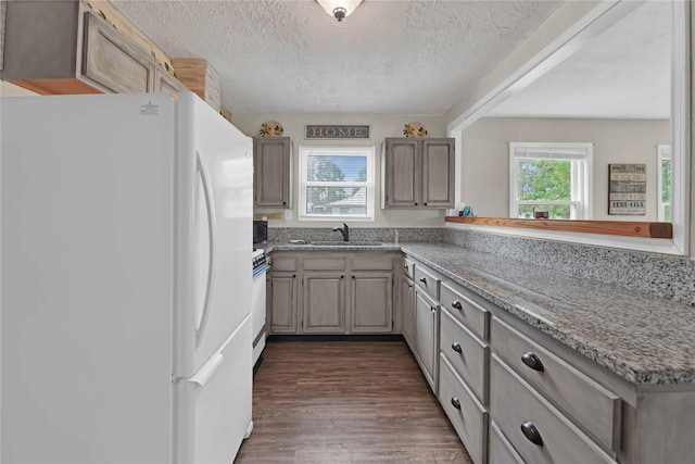 kitchen featuring a textured ceiling, dark hardwood / wood-style flooring, white fridge, sink, and kitchen peninsula