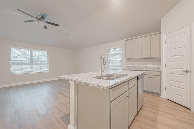 kitchen with dishwasher, light hardwood / wood-style floors, sink, and an island with sink