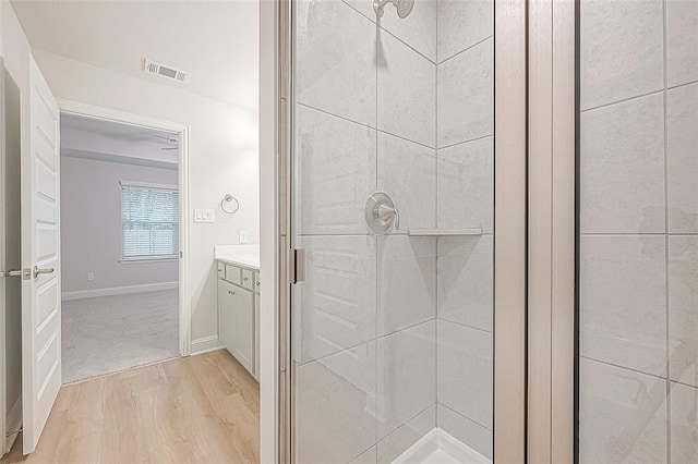 bathroom featuring tiled shower, hardwood / wood-style floors, and vanity