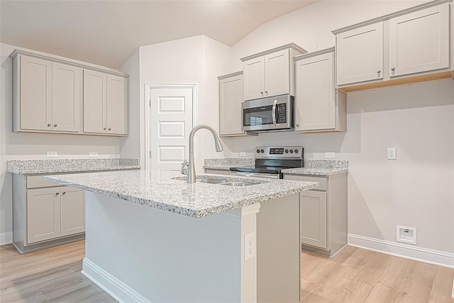 kitchen featuring a kitchen island with sink, sink, light wood-type flooring, and appliances with stainless steel finishes