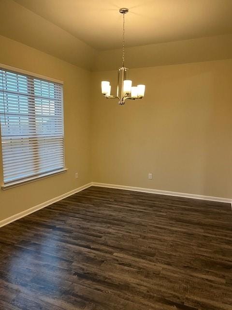 spare room with baseboards, a chandelier, and dark wood-type flooring