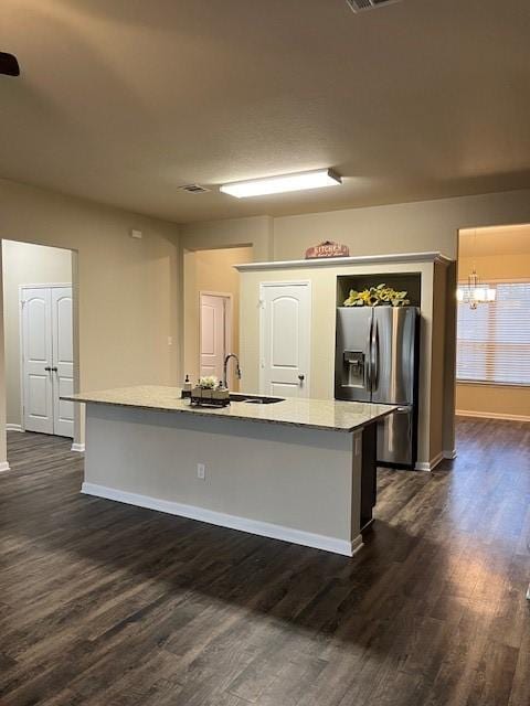 kitchen featuring stainless steel fridge, a kitchen island with sink, dark wood finished floors, and a sink