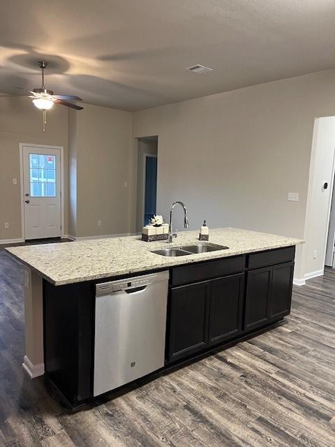 kitchen featuring light stone counters, a sink, stainless steel dishwasher, dark wood finished floors, and a center island with sink