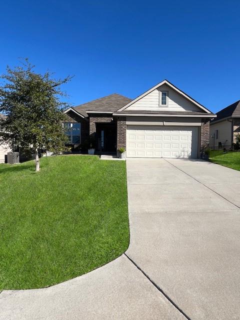 single story home with an attached garage, concrete driveway, brick siding, and a front yard