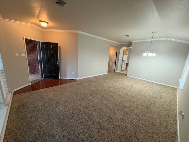 empty room featuring carpet flooring, lofted ceiling, ornamental molding, and a notable chandelier