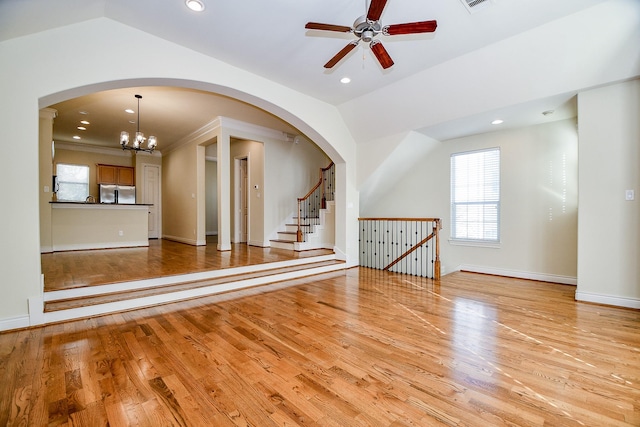 unfurnished living room featuring light hardwood / wood-style flooring, ceiling fan with notable chandelier, and lofted ceiling