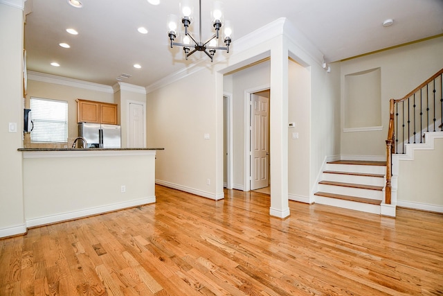 kitchen featuring stainless steel refrigerator, hanging light fixtures, a notable chandelier, light hardwood / wood-style floors, and ornamental molding