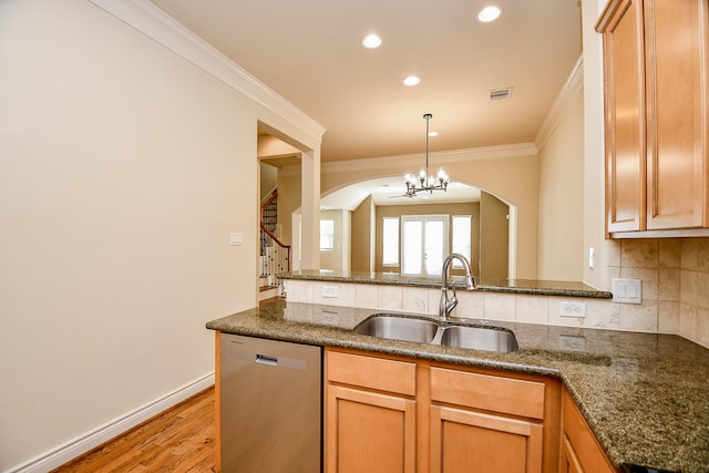 kitchen featuring dishwasher, sink, an inviting chandelier, dark stone counters, and ornamental molding