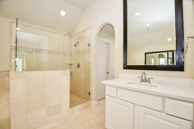 bathroom featuring vanity, tile patterned floors, walk in shower, and vaulted ceiling