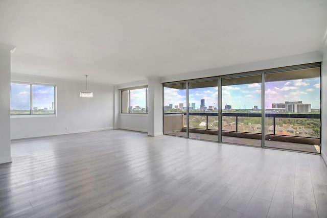 unfurnished room with a notable chandelier and light hardwood / wood-style flooring