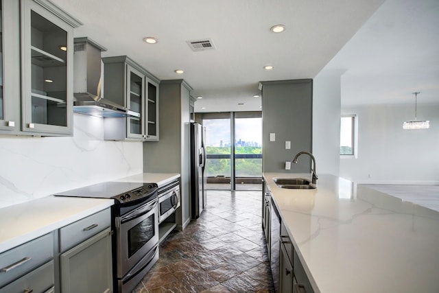 kitchen with pendant lighting, gray cabinetry, sink, wall chimney exhaust hood, and appliances with stainless steel finishes