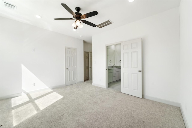 unfurnished bedroom with ceiling fan, light colored carpet, sink, and ensuite bath