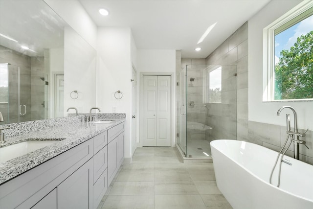 bathroom with tile patterned floors, vanity, a wealth of natural light, and independent shower and bath