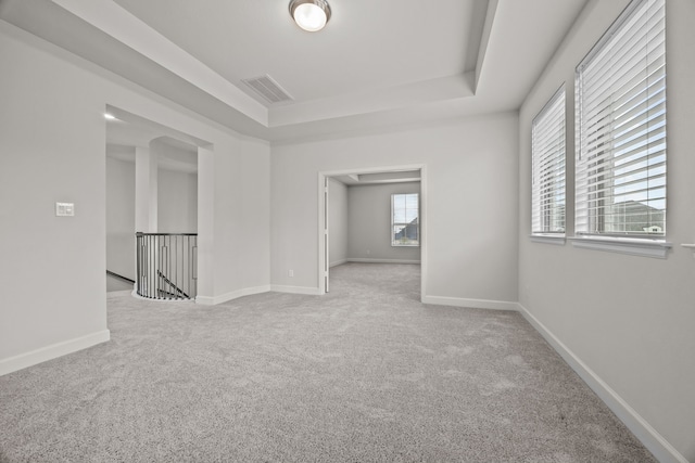 carpeted empty room with a raised ceiling